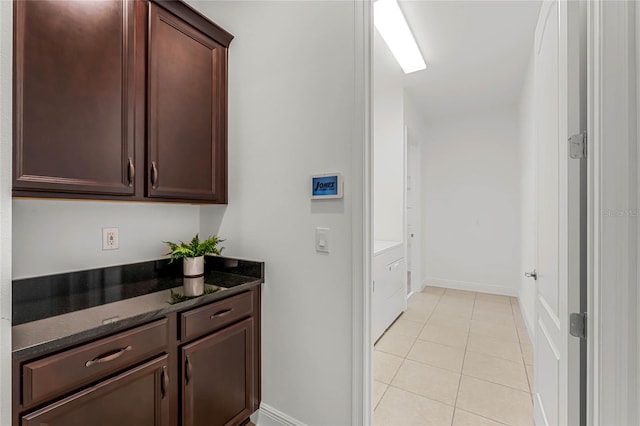 kitchen featuring dark stone countertops, light tile patterned flooring, and dark brown cabinets