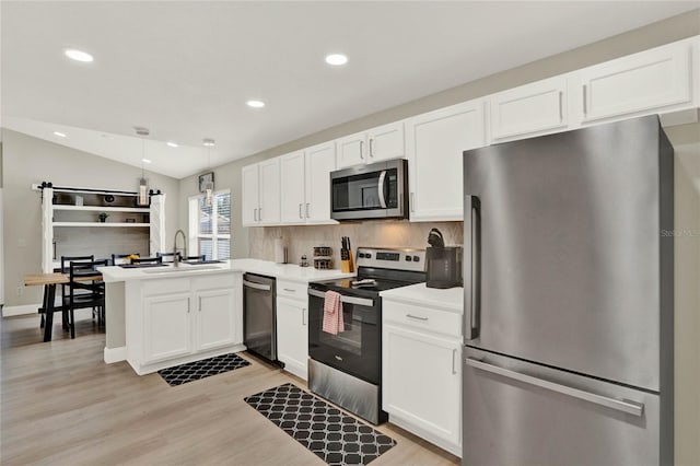 kitchen with appliances with stainless steel finishes, hanging light fixtures, light hardwood / wood-style floors, kitchen peninsula, and lofted ceiling