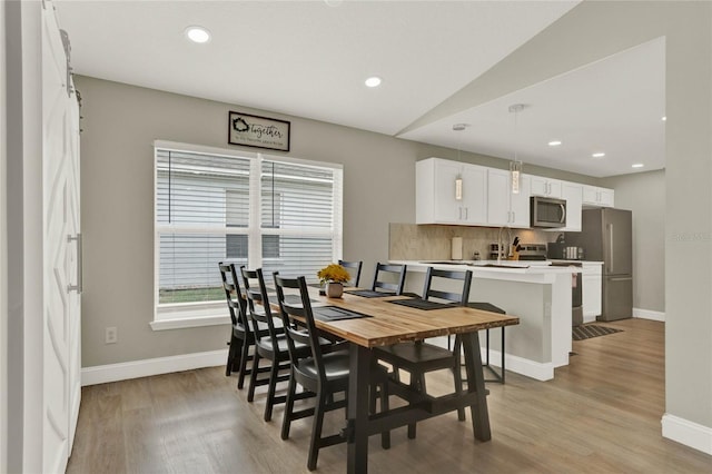 dining space with light hardwood / wood-style floors and lofted ceiling