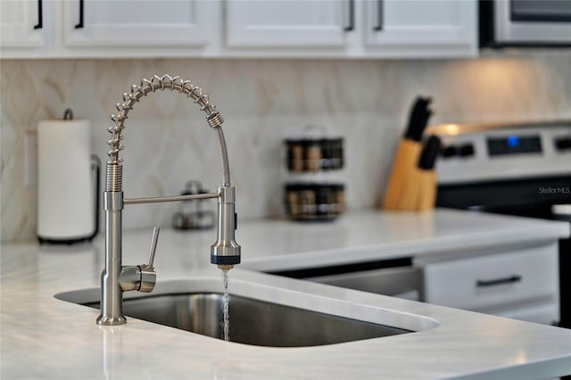 room details featuring white cabinets, sink, and white stove