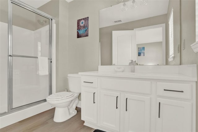 bathroom featuring hardwood / wood-style floors, vanity, toilet, and a shower with door