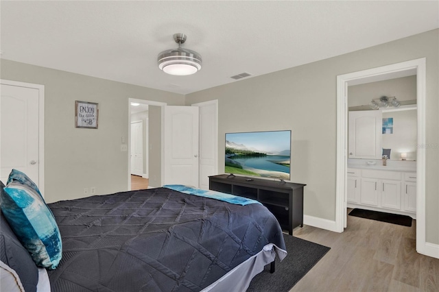 bedroom with light wood-type flooring and ensuite bath