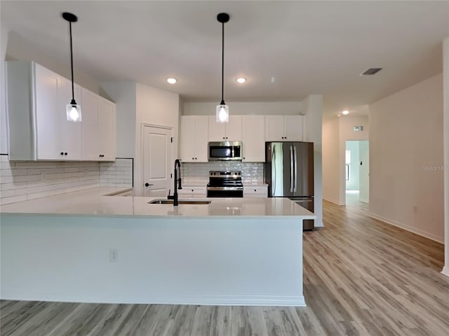 kitchen with white cabinetry, sink, stainless steel appliances, and decorative light fixtures