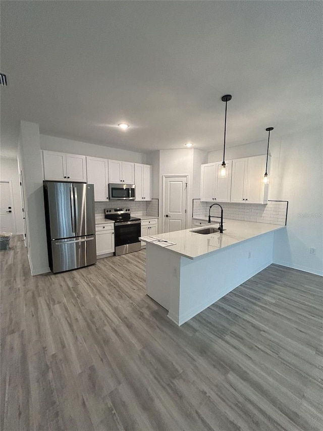 kitchen with white cabinetry, kitchen peninsula, appliances with stainless steel finishes, and sink