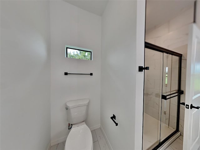 bathroom featuring a shower with shower door and toilet