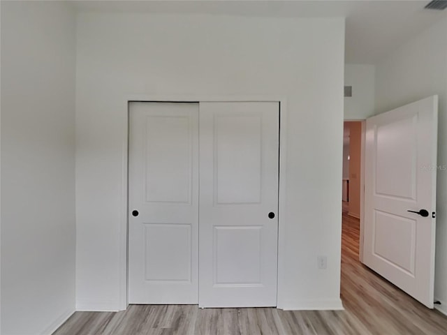 unfurnished bedroom with a closet and light wood-type flooring