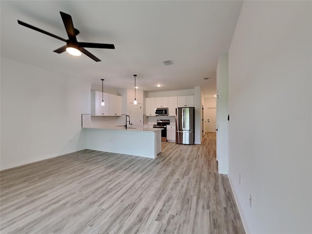 kitchen with white cabinets, kitchen peninsula, stainless steel appliances, decorative light fixtures, and ceiling fan