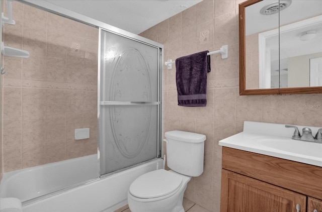 full bathroom with tile walls, enclosed tub / shower combo, toilet, and vanity