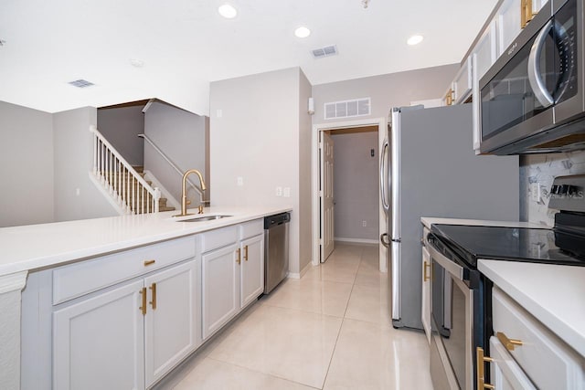 kitchen with appliances with stainless steel finishes, white cabinetry, sink, and light tile patterned floors