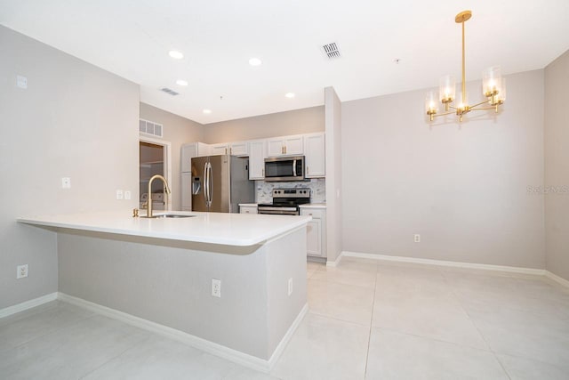 kitchen featuring white cabinets, appliances with stainless steel finishes, hanging light fixtures, and sink