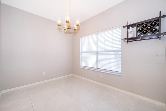 empty room featuring an inviting chandelier and light tile patterned floors