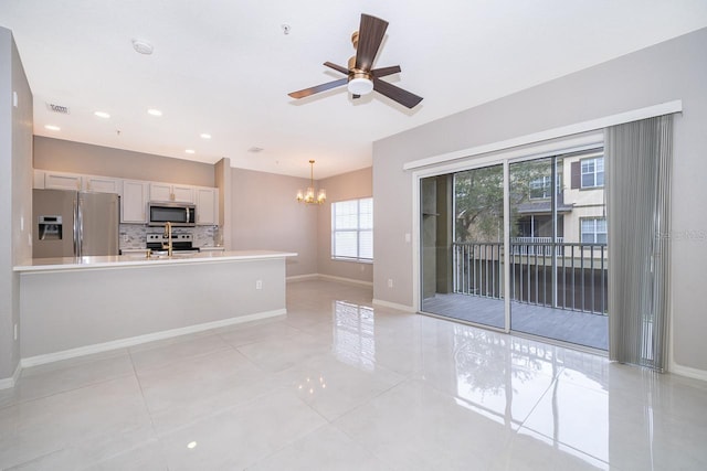 kitchen featuring light tile patterned flooring, ceiling fan with notable chandelier, white cabinets, appliances with stainless steel finishes, and decorative light fixtures