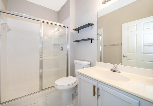 bathroom featuring a shower with door, vanity, and toilet