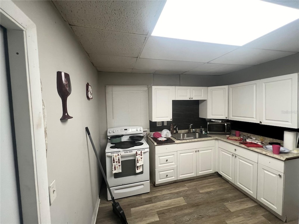 kitchen featuring white electric range oven, dark wood-type flooring, sink, and white cabinetry