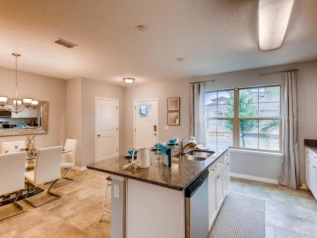 kitchen featuring sink, dishwasher, white cabinetry, a kitchen island with sink, and hanging light fixtures