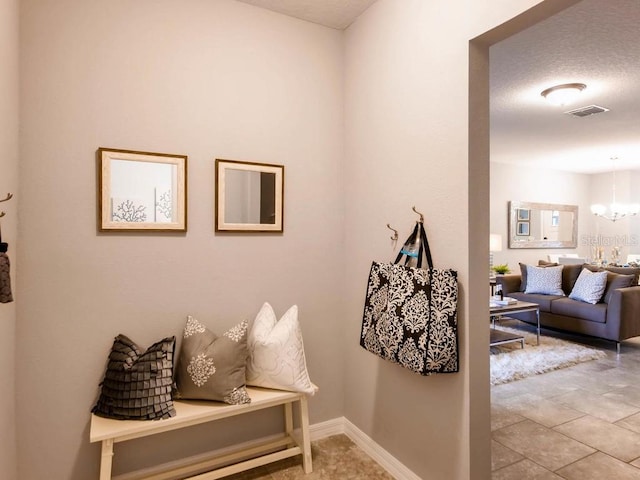 mudroom with tile patterned floors, a textured ceiling, and an inviting chandelier