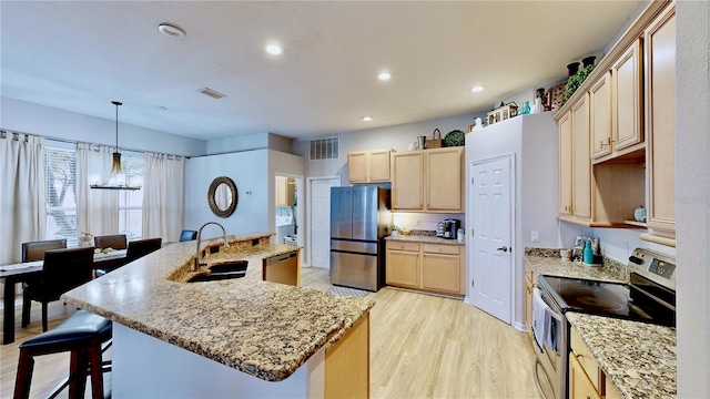 kitchen featuring sink, decorative light fixtures, stainless steel appliances, light brown cabinetry, and light wood-type flooring