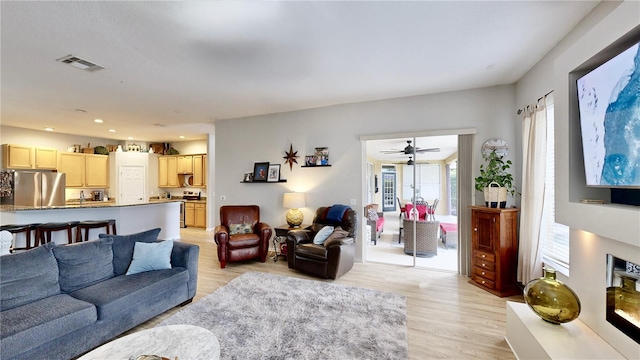 living room featuring ceiling fan and light hardwood / wood-style flooring