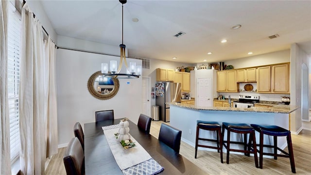 dining space with light wood-type flooring and a notable chandelier