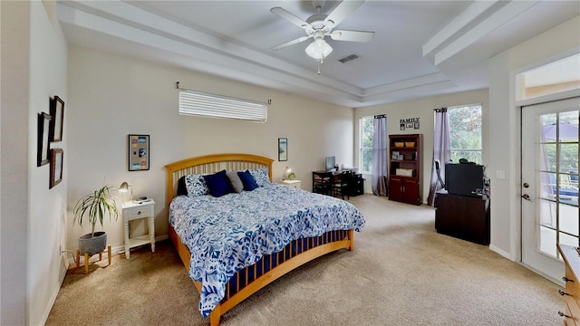 carpeted bedroom featuring ceiling fan, a tray ceiling, and access to outside