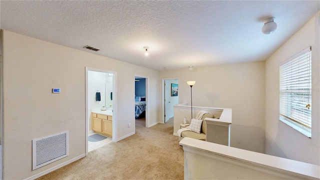 corridor with light colored carpet and a textured ceiling