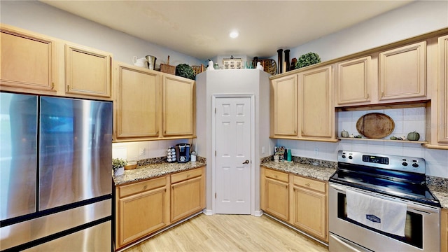 kitchen featuring light stone counters, light brown cabinetry, appliances with stainless steel finishes, and light wood-type flooring