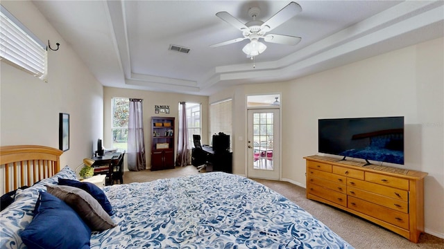 bedroom with light carpet, ceiling fan, and a raised ceiling