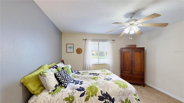 carpeted bedroom featuring ceiling fan and a textured ceiling