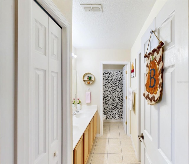 bathroom featuring vanity, walk in shower, tile patterned flooring, toilet, and a textured ceiling