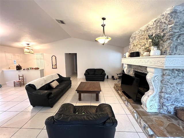 living room with a stone fireplace, lofted ceiling, and light tile patterned floors