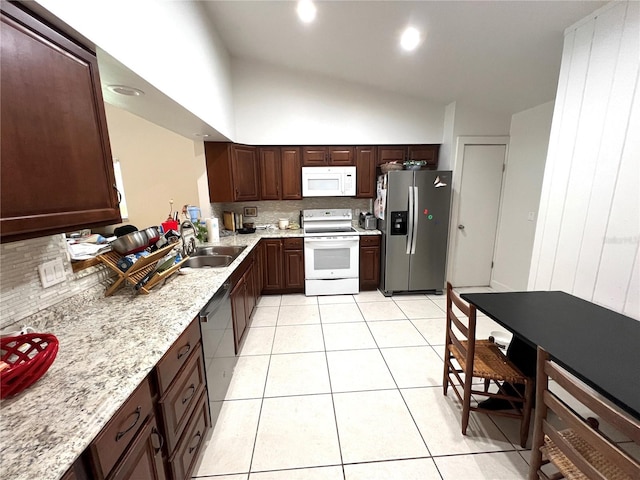 kitchen with light stone countertops, appliances with stainless steel finishes, light tile patterned floors, and sink