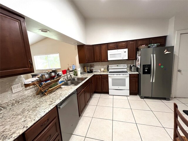 kitchen featuring light stone counters, sink, stainless steel appliances, backsplash, and light tile patterned floors