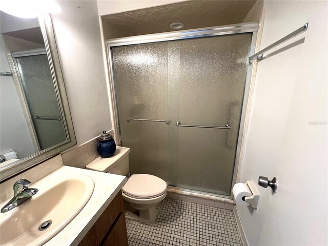 bathroom featuring walk in shower, vanity, tile patterned flooring, and toilet