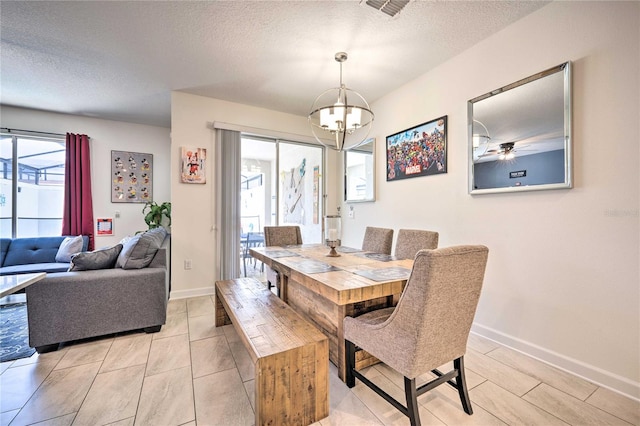 dining area featuring a textured ceiling, ceiling fan with notable chandelier, and a healthy amount of sunlight