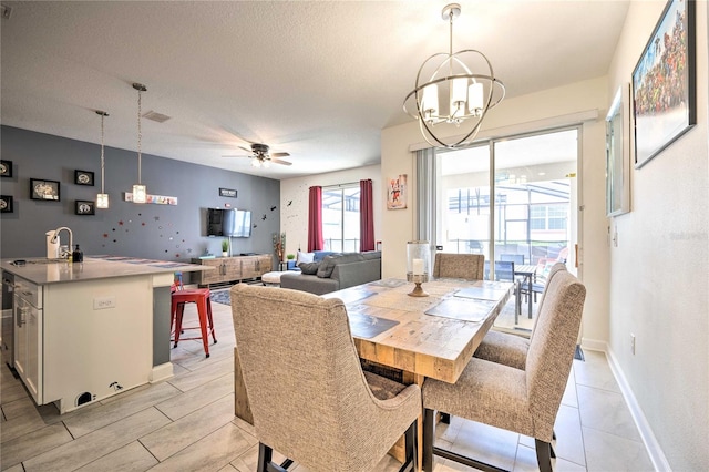 dining room with a textured ceiling, sink, and ceiling fan with notable chandelier