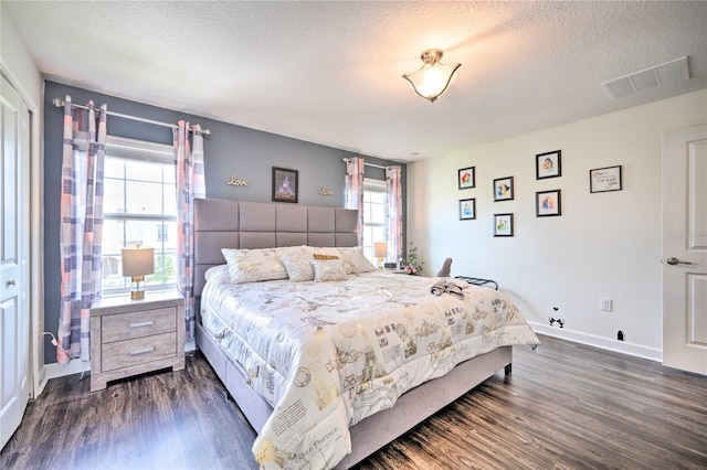 bedroom featuring multiple windows, a textured ceiling, and dark hardwood / wood-style flooring