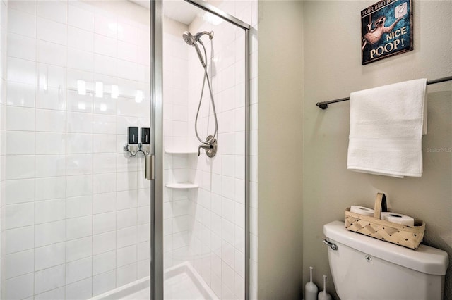 bathroom featuring a shower with door and toilet