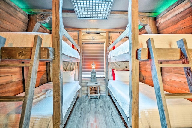 bedroom with wood-type flooring and wooden walls