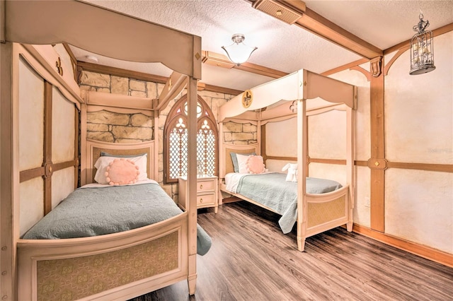 bedroom featuring beamed ceiling, wood-type flooring, and a textured ceiling