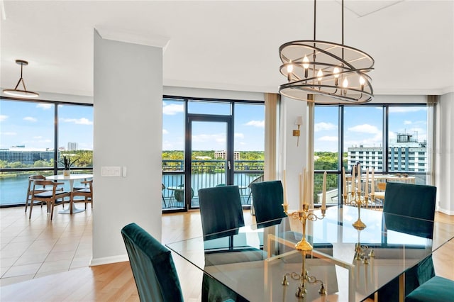 dining space with light hardwood / wood-style flooring, a water view, an inviting chandelier, and crown molding