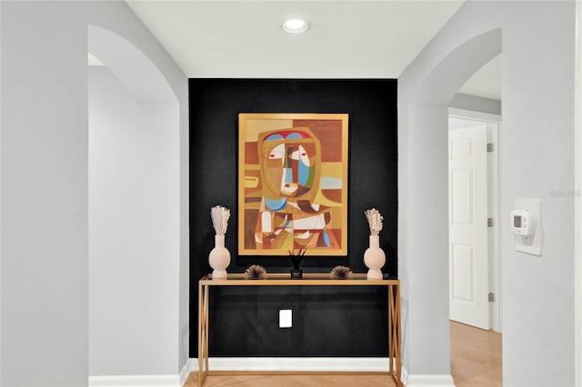 interior details featuring arched walkways, baseboards, recessed lighting, and an accent wall