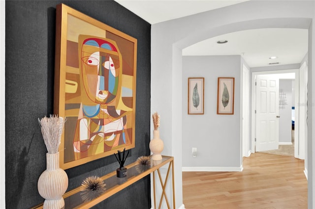 hallway featuring arched walkways, recessed lighting, baseboards, wood finished floors, and visible vents