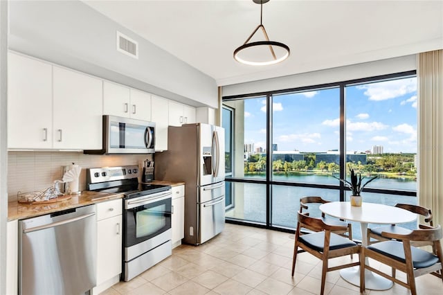 kitchen with visible vents, tasteful backsplash, white cabinets, a water view, and stainless steel appliances