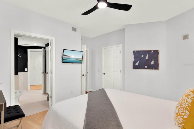 bedroom featuring light hardwood / wood-style floors, ceiling fan, and ensuite bathroom