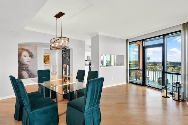 dining area with crown molding, arched walkways, baseboards, light wood finished floors, and a chandelier