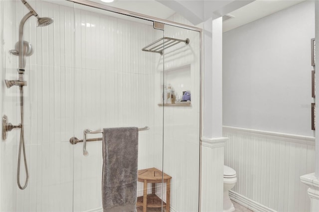 bathroom with wainscoting, a shower stall, and toilet