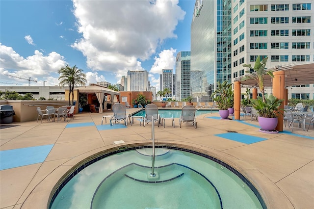 view of pool with a view of city, a gazebo, a community hot tub, and a patio area