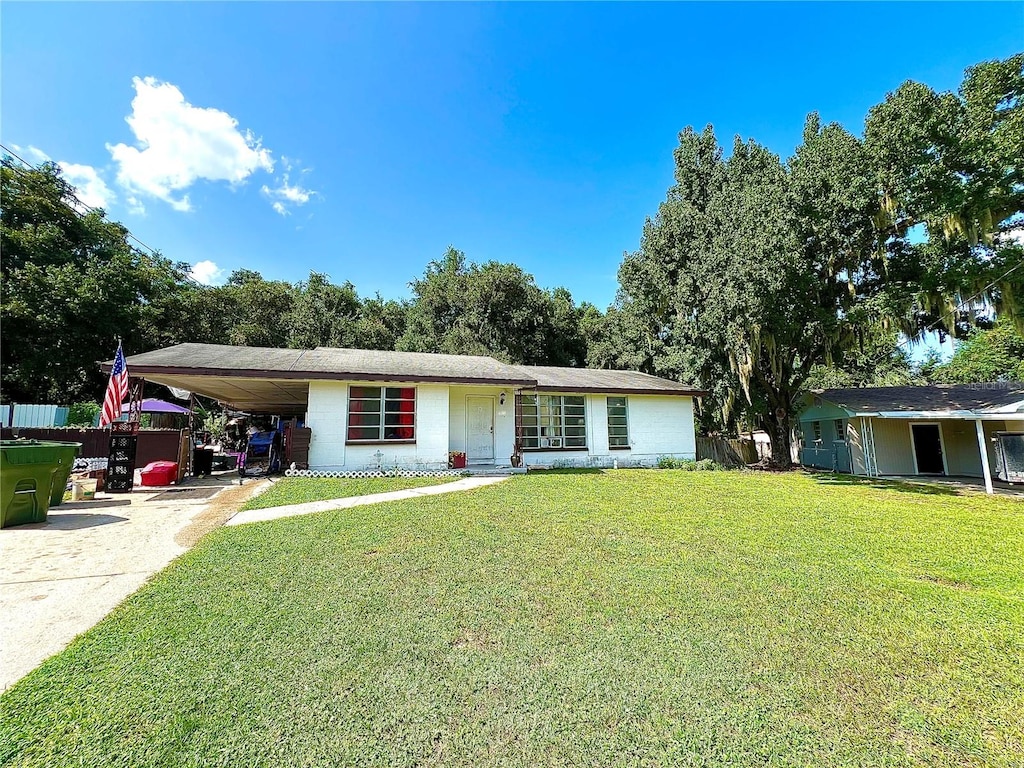 ranch-style home featuring a carport and a front lawn