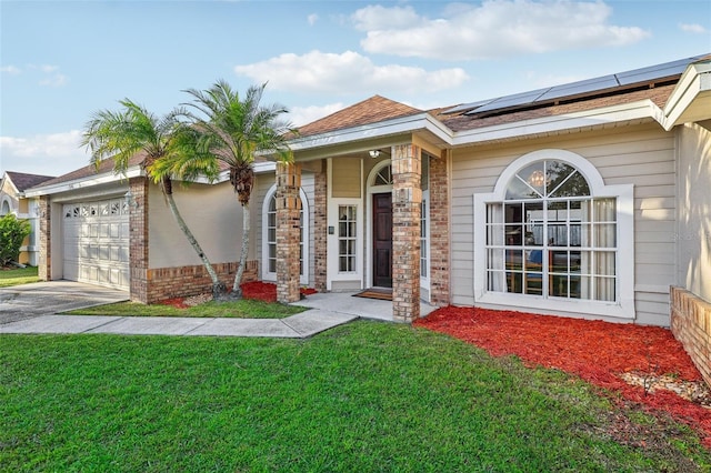 view of front of house with a front yard, solar panels, and a garage