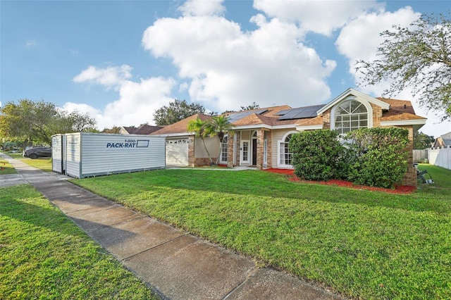 single story home with a front yard, a garage, and solar panels